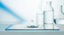 A single clear droplet of pure water rippling on a still surface in a minimalist laboratory setting, conveying water purity and scientific stillness